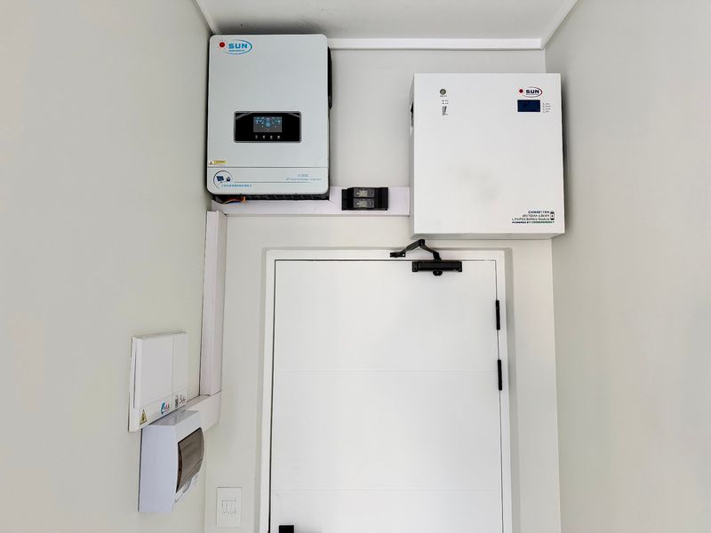 A utility area featuring a wall-mounted solar hybrid inverter and lithium battery storage system, ensuring efficient energy management for the penthouse.