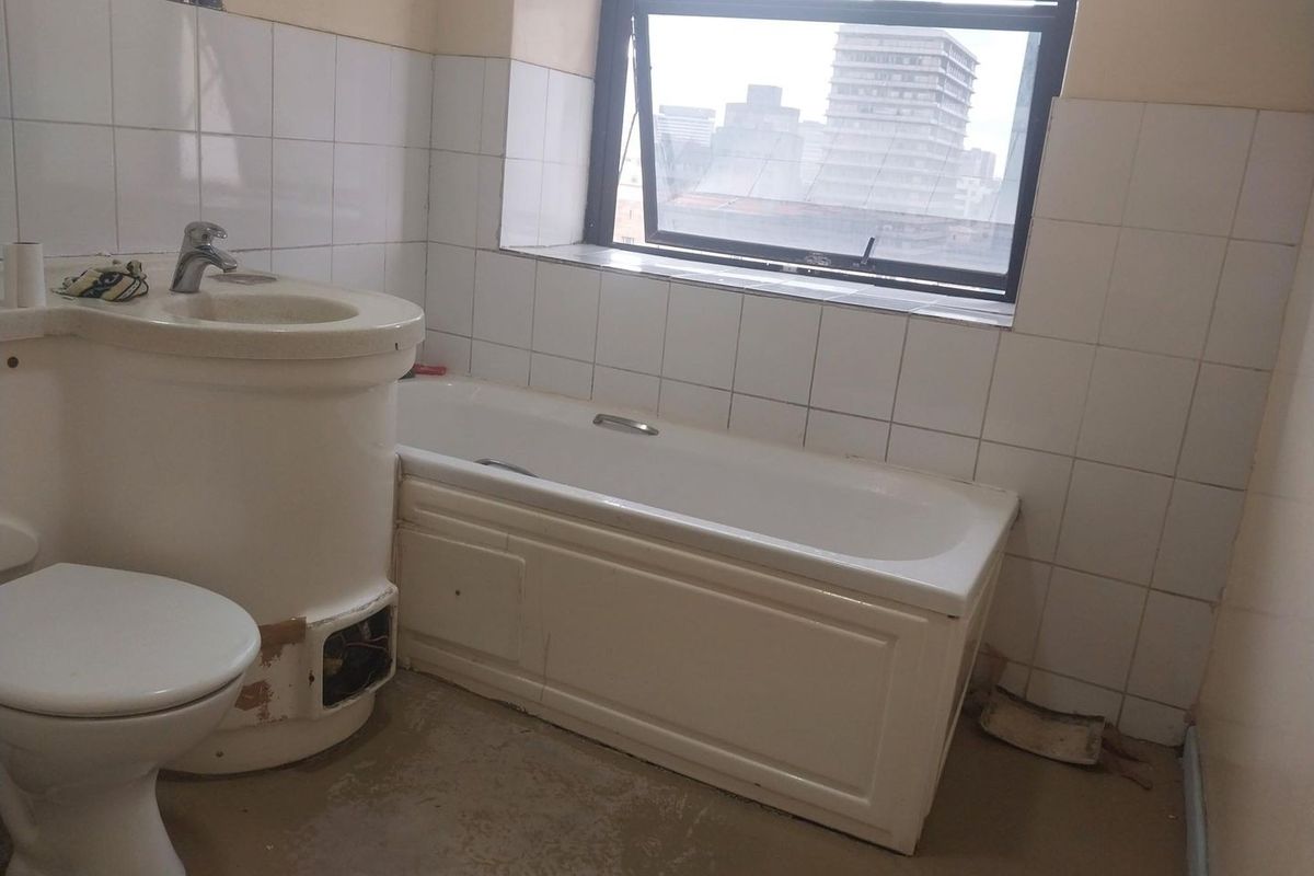 A dated bathroom featuring a bathtub, pedestal basin, and toilet, requiring significant renovation and new floor finishes to restore functionality and aesthetic appeal.