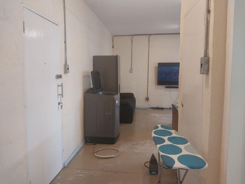 A utility space featuring exposed electrical conduit and worn flooring, suitable for conversion into a functional laundry or storage area.