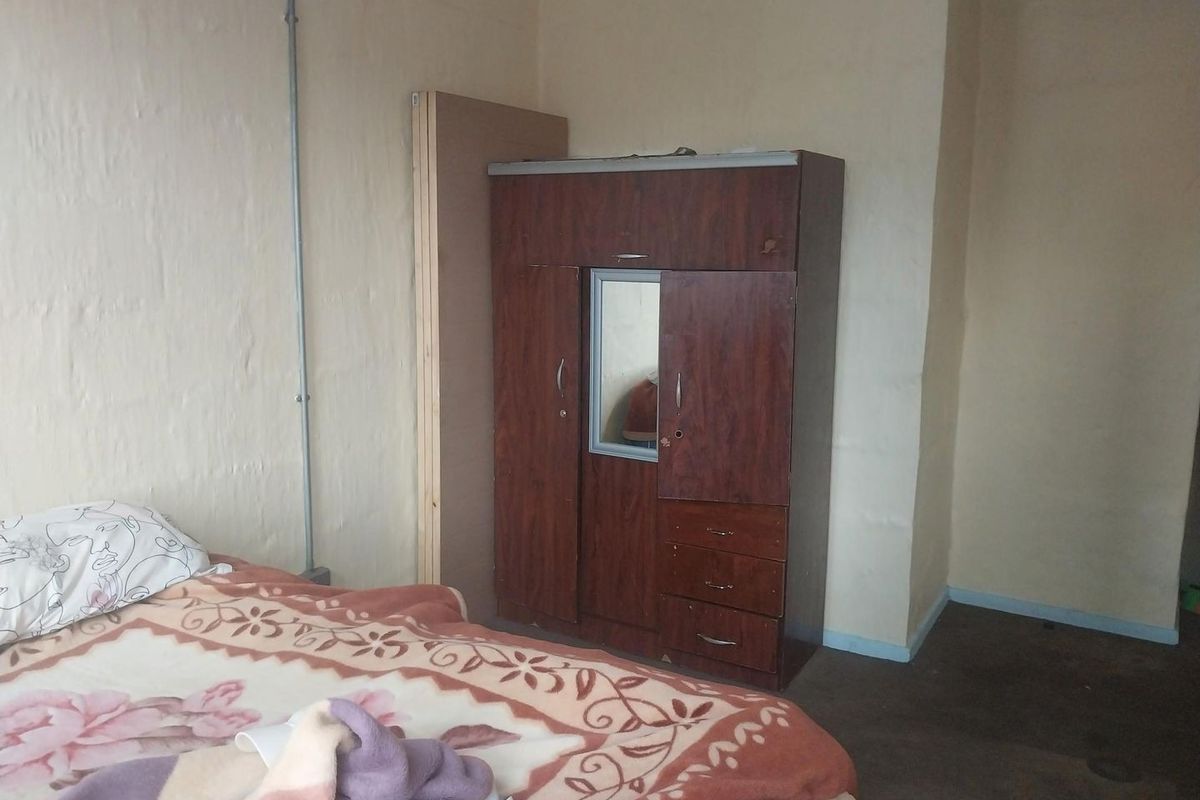 A bedroom featuring plain walls with exposed electrical conduit and basic flooring, requiring cosmetic updates to improve the overall aesthetic.