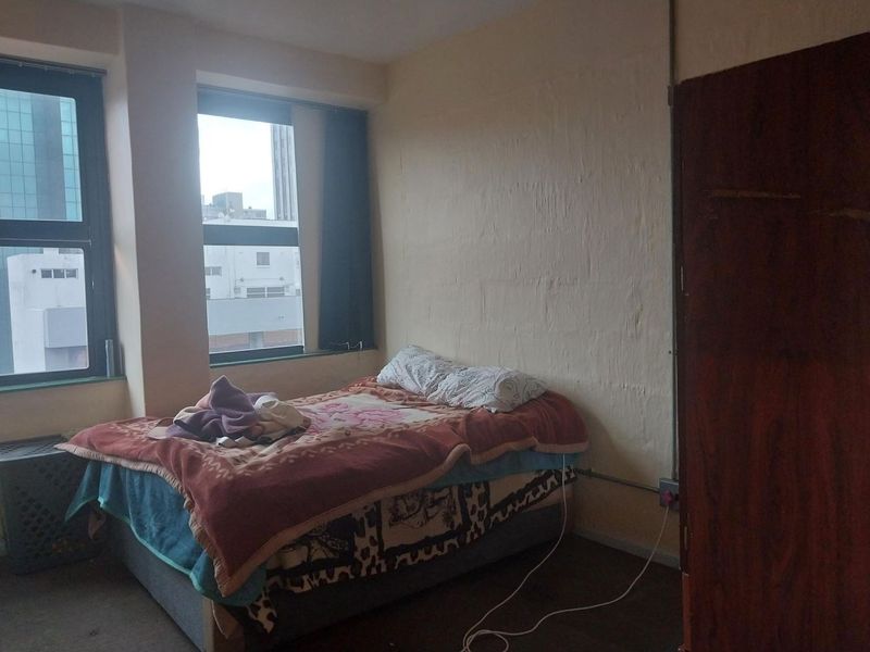 A bedroom featuring aluminium window frames and exposed electrical conduit, requiring cosmetic updates to improve the overall finish and aesthetic appeal.