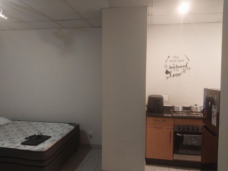 Open plan studio apartment featuring a compact kitchenette with built-in cabinetry, granite countertops, and an integrated electric stove and oven.