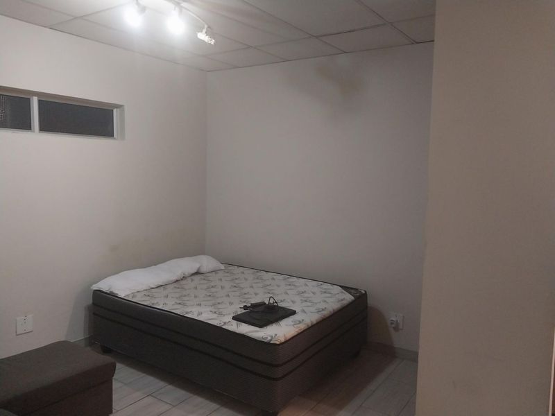 A basic bedroom featuring tiled flooring, a drop ceiling, and a high-level window, providing a functional space ready for cosmetic updates.