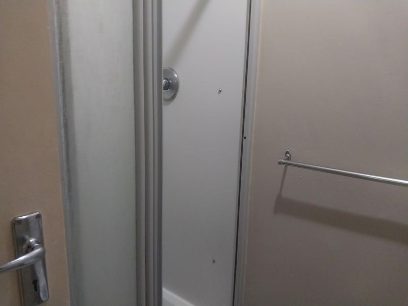 A functional bathroom space featuring a shower enclosure with a mixer and a wall-mounted towel rail.