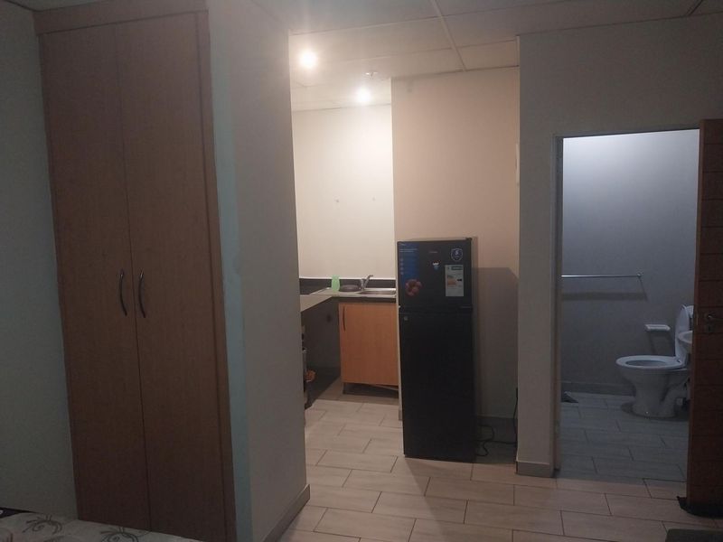 Open plan studio apartment featuring a kitchenette with sink, built-in wardrobe, and an adjacent private bathroom with toilet.