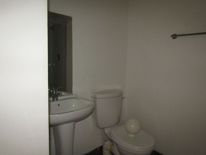 A compact bathroom featuring a pedestal washbasin, toilet, and wall-mounted towel rail, requiring cosmetic updates to improve its overall appeal.