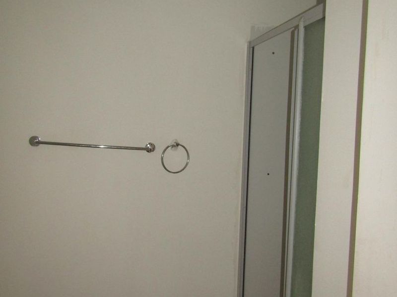 A functional bathroom featuring a shower enclosure, chrome towel fixtures, and neutral wall finishes.