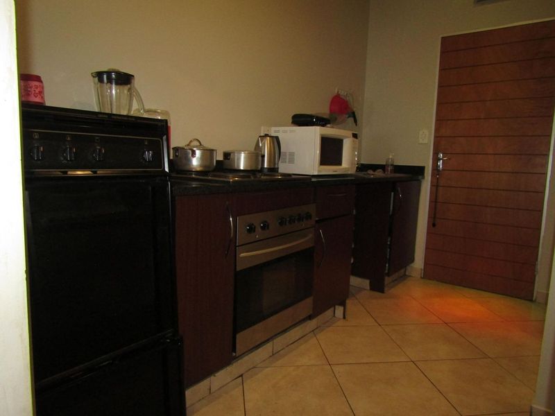 A functional kitchen area featuring dark wood cabinetry, stone countertops, a built-in oven, and tiled flooring, providing a practical workspace.