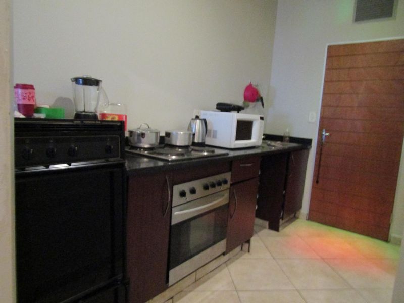 A functional kitchen featuring dark wood cabinetry, granite countertops, a built-in oven, and tiled flooring, providing a practical workspace.