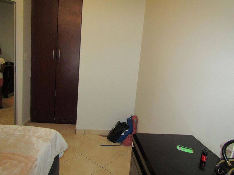 A bedroom featuring tiled flooring and a dark wood built-in wardrobe.