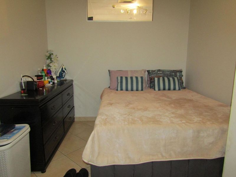 A compact bedroom featuring tiled flooring and neutral wall finishes, providing a functional sleeping space.