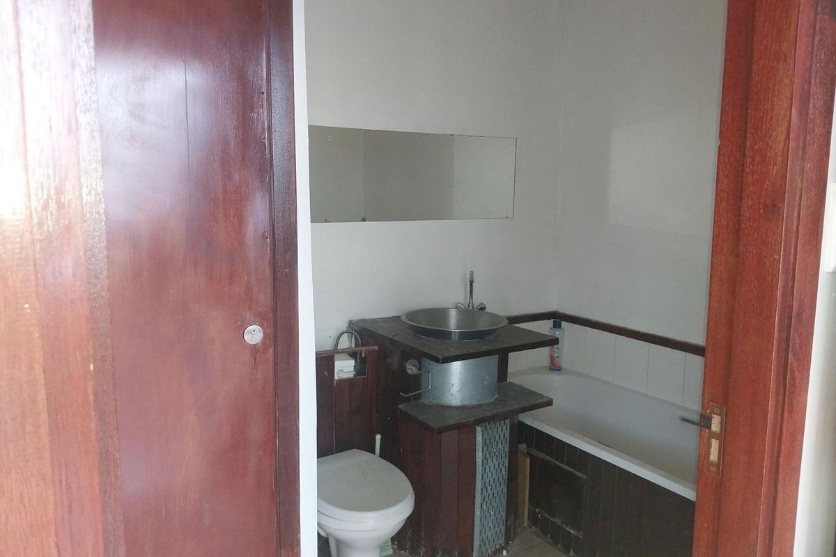 A compact bathroom featuring a bathtub, toilet, and a basin with a vanity unit, requiring cosmetic updates to modernize the space.