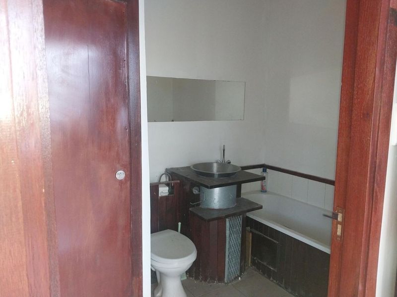 A compact bathroom featuring a bathtub, toilet, and a basin with a vanity unit, requiring cosmetic updates to modernize the space.