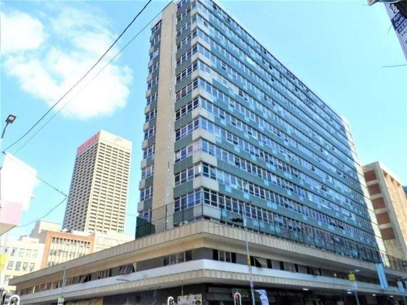 A view of a multi-story apartment building facade featuring a grid of windows and concrete structural elements in an urban setting.