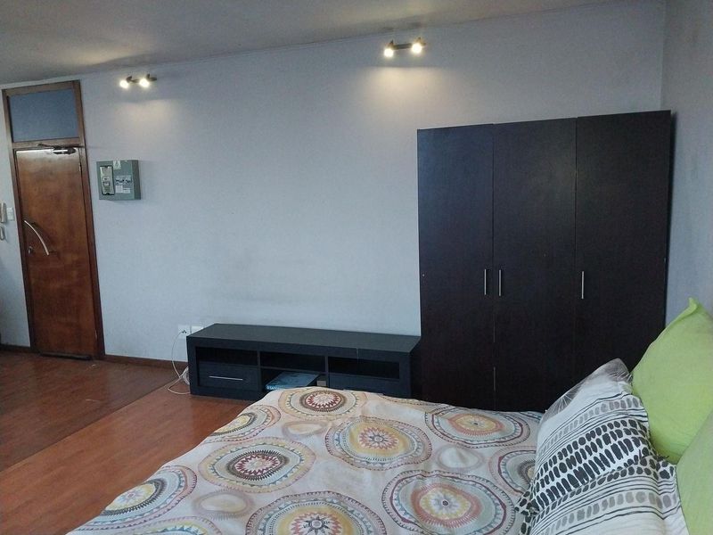 A bedroom featuring laminate flooring, built-in wardrobe storage, and modern spotlight fixtures, providing a functional and neutral living space.