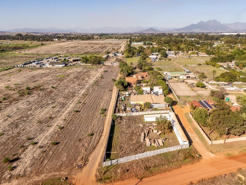 Aerial view of a vacant residential land plot featuring perimeter fencing and access to a dirt road in a rural setting.