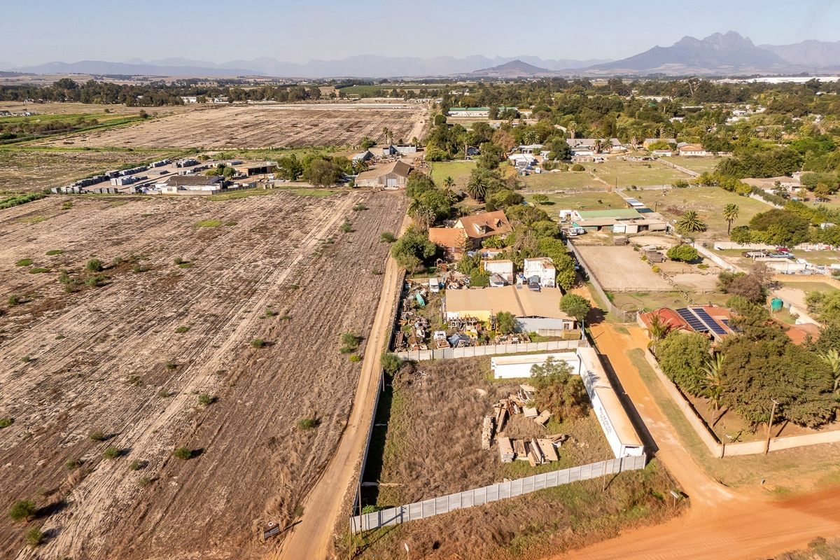 Aerial view of a vacant residential land plot featuring perimeter fencing and access to a dirt road in a rural setting.