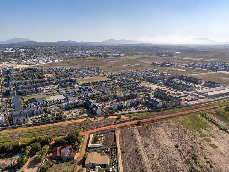 An aerial view showing the surrounding residential neighborhood, nearby railway infrastructure, and adjacent undeveloped land parcels.