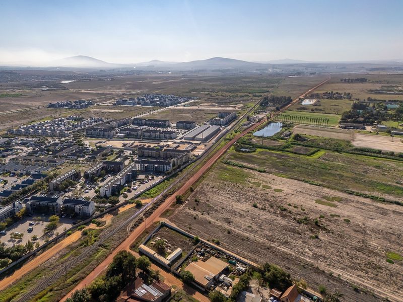 Aerial view of the vacant land parcel showing surrounding residential developments, railway infrastructure, and open landscape.