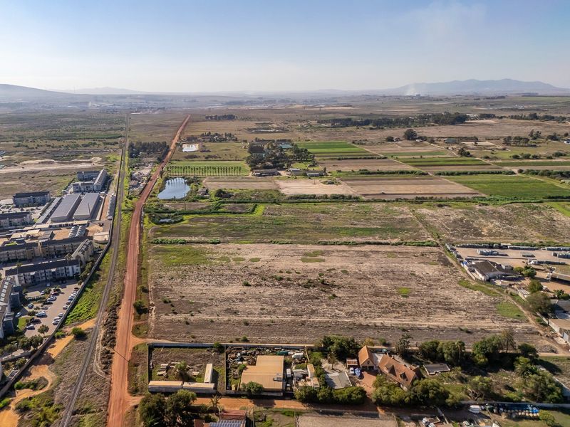An aerial view of a large tract of vacant land adjacent to a railway line and rural landscape.