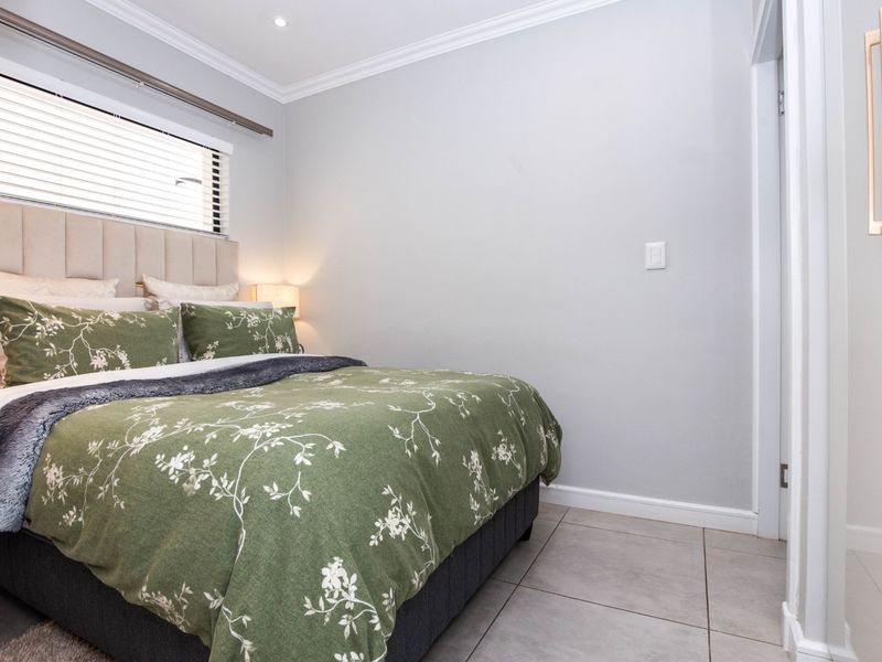 A well-maintained bedroom featuring neutral tiled flooring, recessed downlighting, crown molding, and venetian blinds.