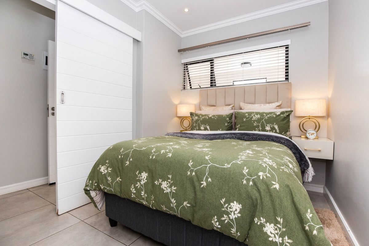 A well-maintained bedroom featuring tiled flooring, a modern sliding door, and horizontal window blinds, creating a clean and functional living space.