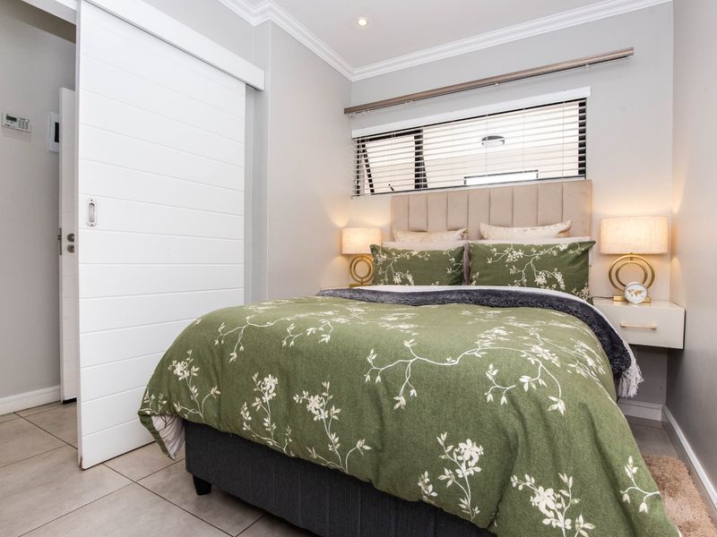 A well-maintained bedroom featuring tiled flooring, a modern sliding door, and horizontal window blinds, creating a clean and functional living space.