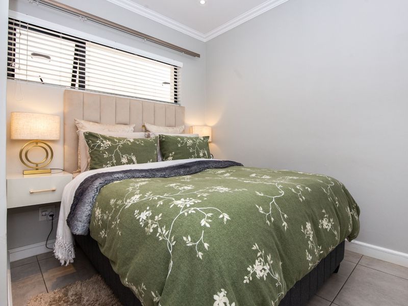 A well-maintained bedroom featuring tiled flooring, recessed downlighting, crown molding, and a window fitted with venetian blinds.