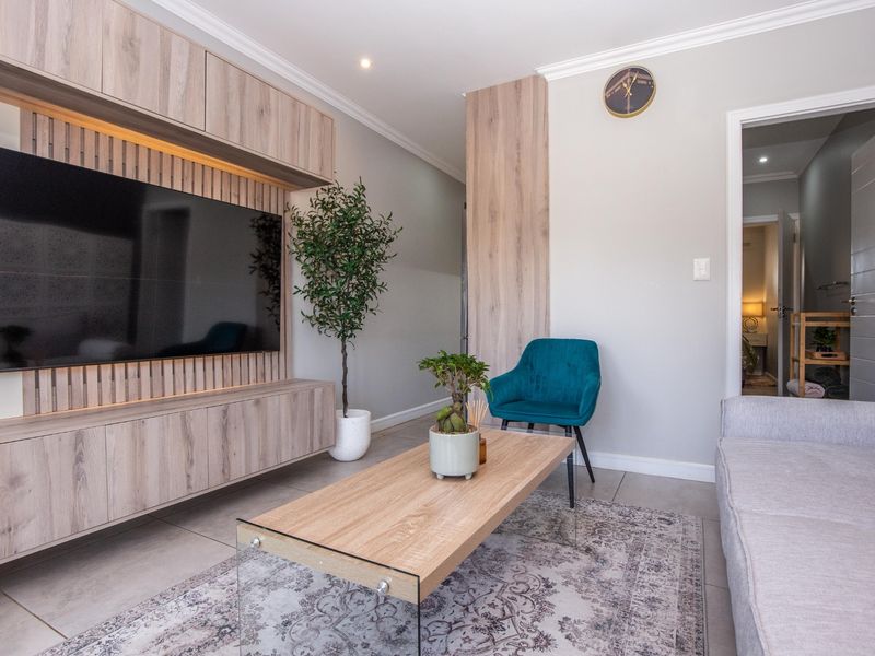 Modern living room featuring a custom built-in media unit with integrated lighting, neutral tiled flooring, and elegant coving details.