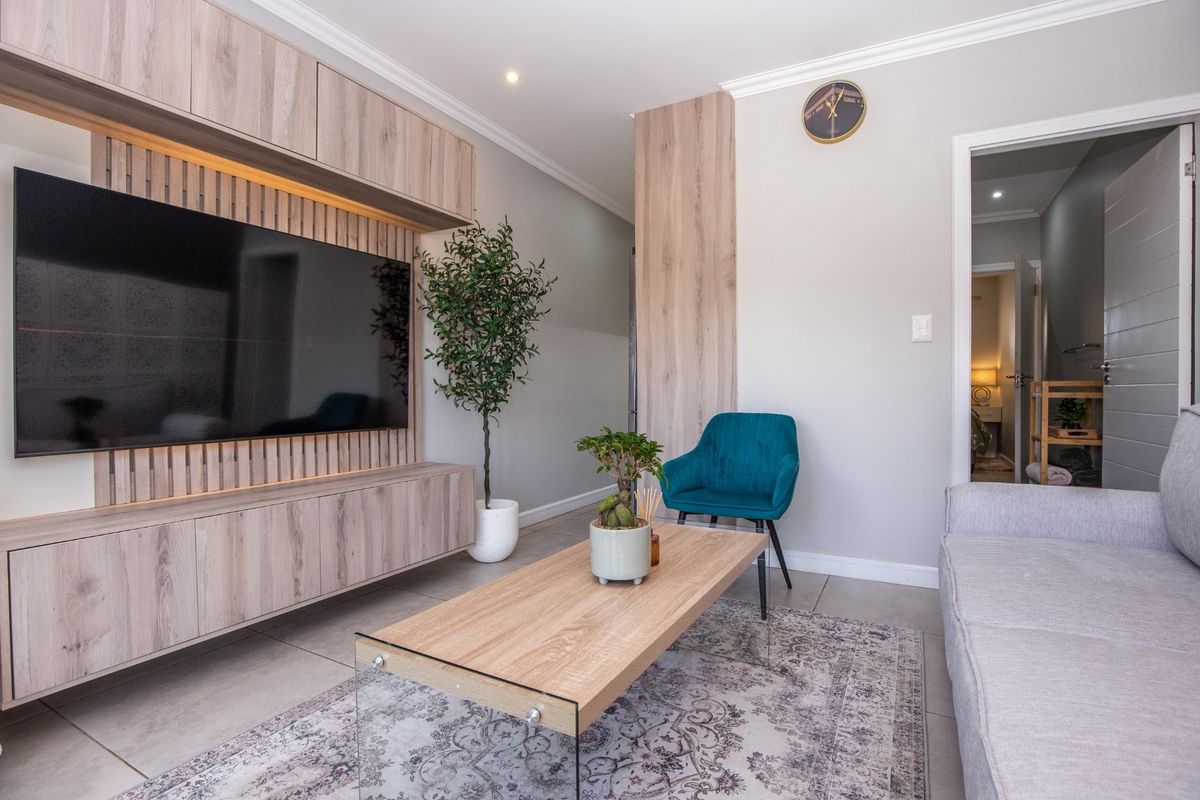 Modern living room featuring a custom built-in media unit with integrated lighting, neutral tiled flooring, and elegant coving details.