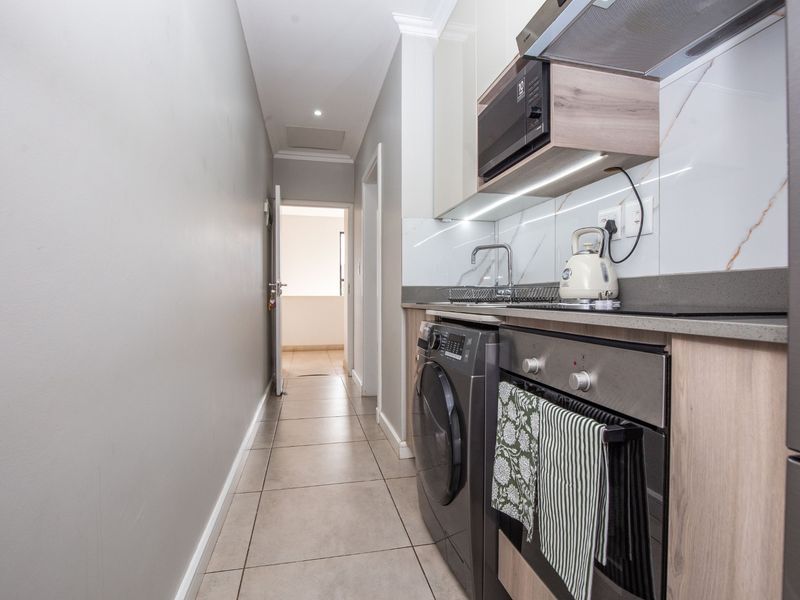 Modern galley-style kitchen featuring sleek cabinetry, stone countertops, integrated appliances, and high-quality marble-look splashback finishes.