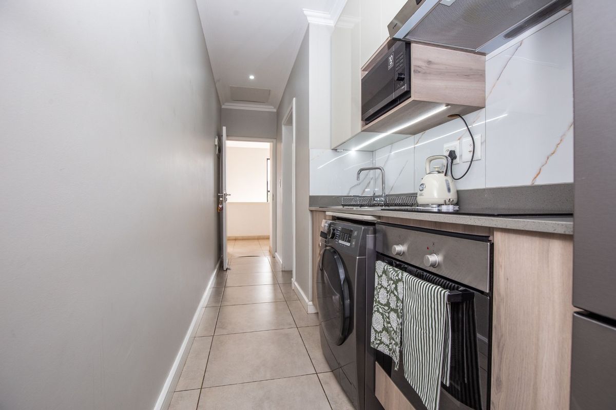 Modern galley-style kitchen featuring sleek cabinetry, stone countertops, integrated appliances, and high-quality marble-look splashback finishes.
