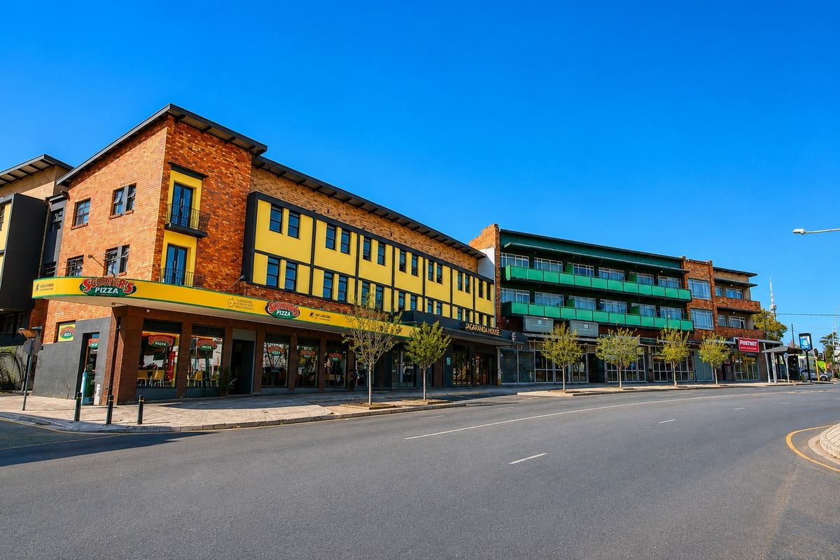 A well-maintained commercial building complex featuring brick facades, multiple storefronts, and upper-level balconies along a paved street.
