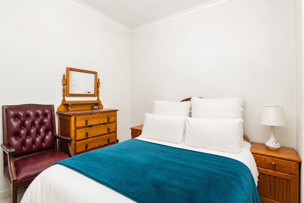 A well-maintained bedroom featuring neutral walls, coving, and classic timber finishes, providing a comfortable and functional sleeping space.