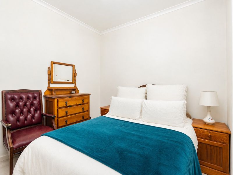 A well-maintained bedroom featuring neutral walls, coving, and classic timber finishes, providing a comfortable and functional sleeping space.