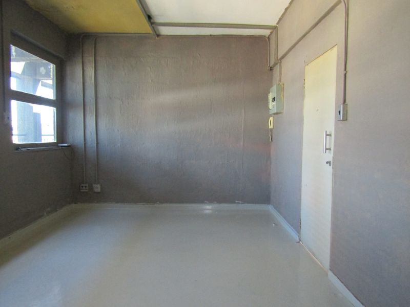 An empty bedroom featuring exposed electrical conduits and basic finishes, requiring renovation to improve the aesthetic and overall condition of the space.