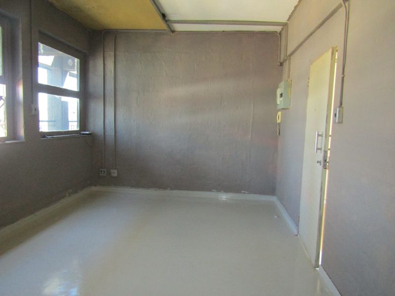 An empty bedroom featuring exposed electrical conduit, an intercom system, and basic finishes, requiring renovation to improve its aesthetic and functional appeal.