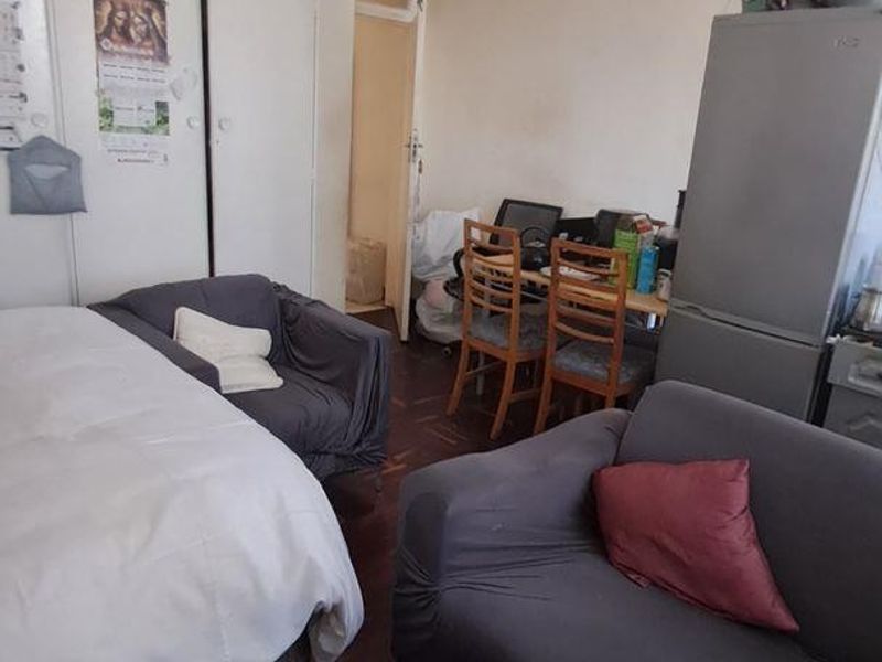A compact bedroom featuring built-in cupboards and parquet flooring, offering a functional layout with potential for modernization.