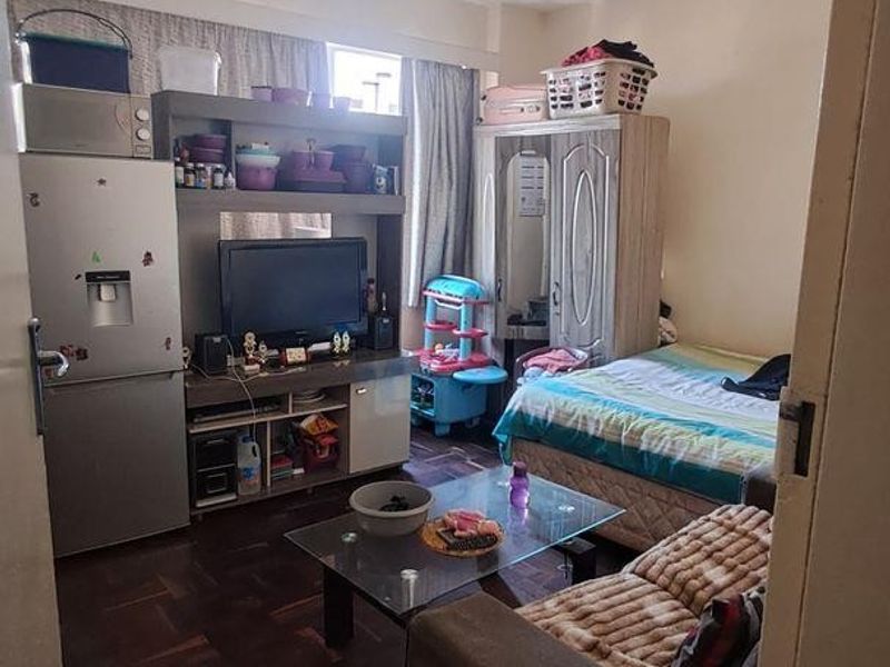 A bedroom featuring parquet flooring and large windows with curtain tracks, offering a functional living space.