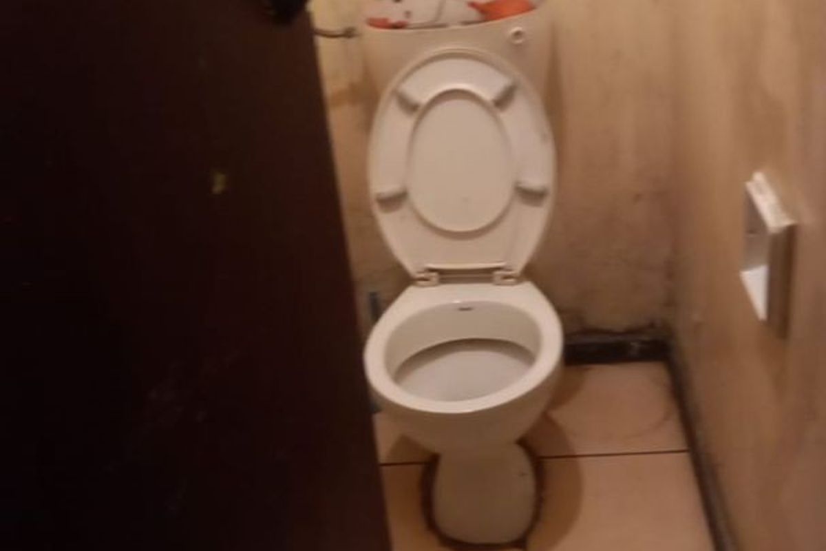 A small, dated bathroom featuring a toilet and tiled flooring, currently requiring significant cosmetic repairs and wall refinishing.