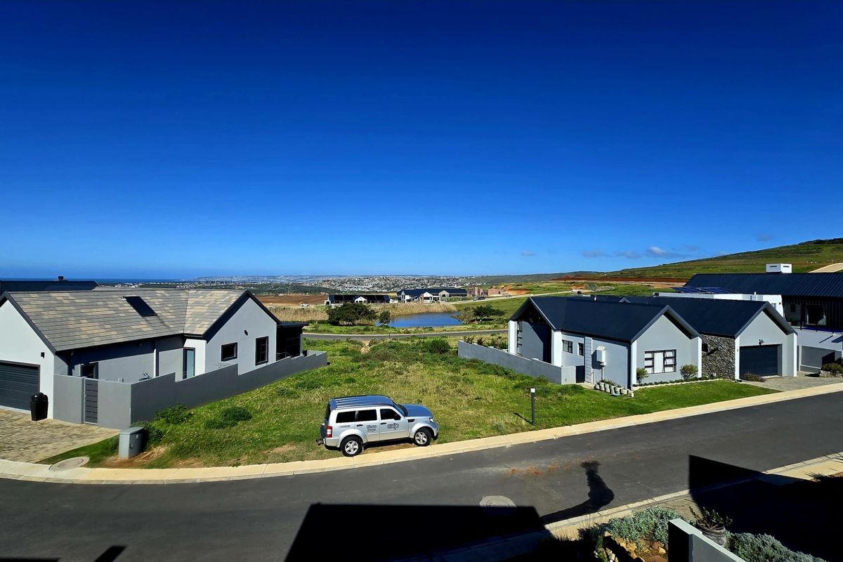 An elevated aerial view of a modern residential estate featuring contemporary homes with tiled roofs, paved driveways, and surrounding landscaped grounds.