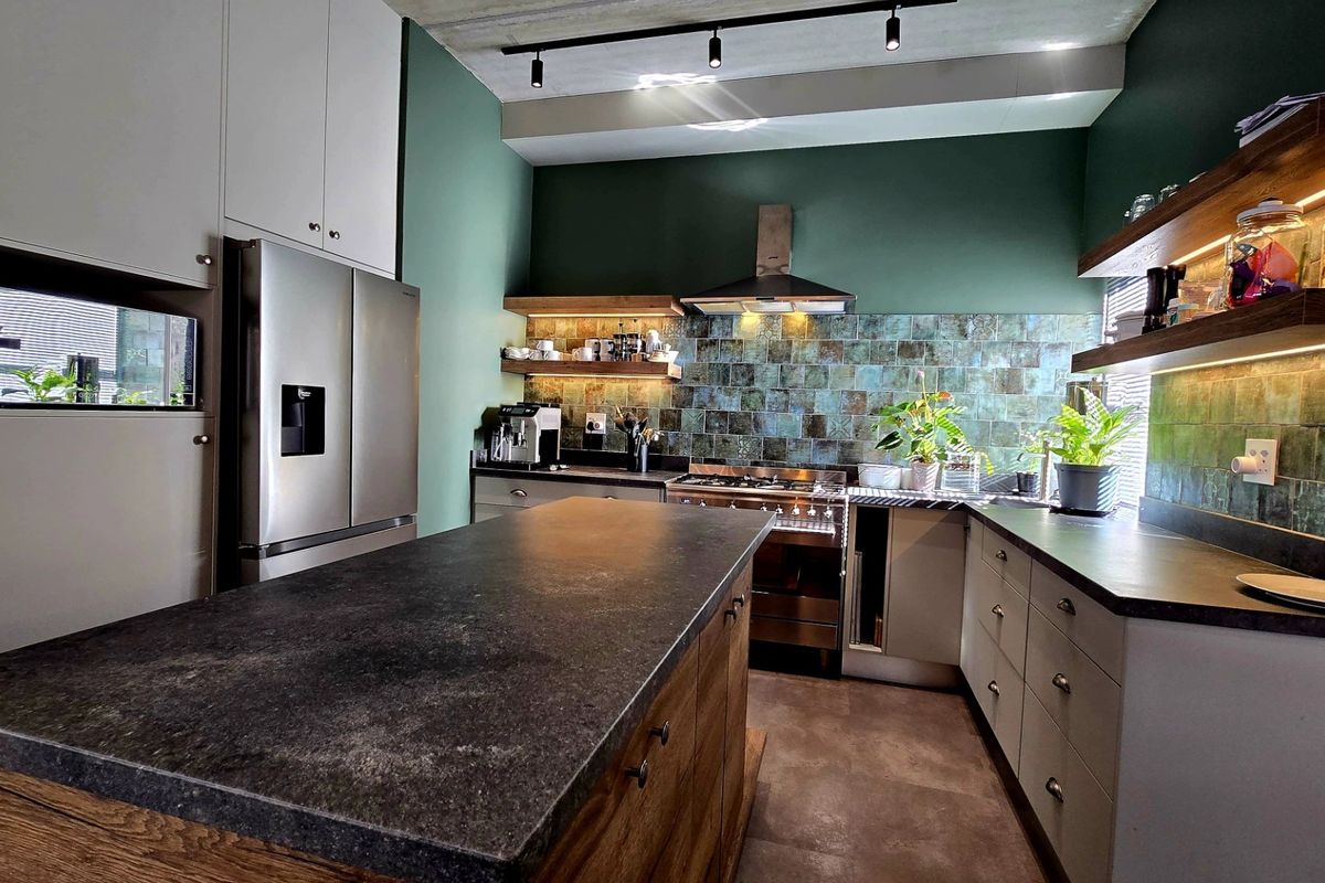 Modern kitchen featuring a central island, stone countertops, tiled backsplash, floating shelves with integrated lighting, and high-quality built-in cabinetry.