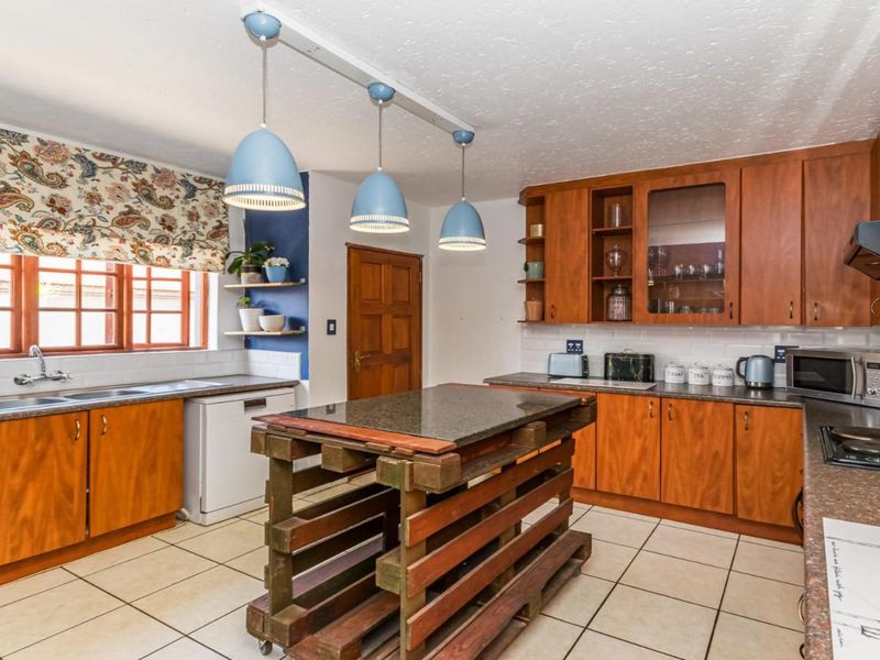 A functional kitchen featuring wooden cabinetry, laminate countertops, a double basin sink, and a built-in hob with an extractor fan.