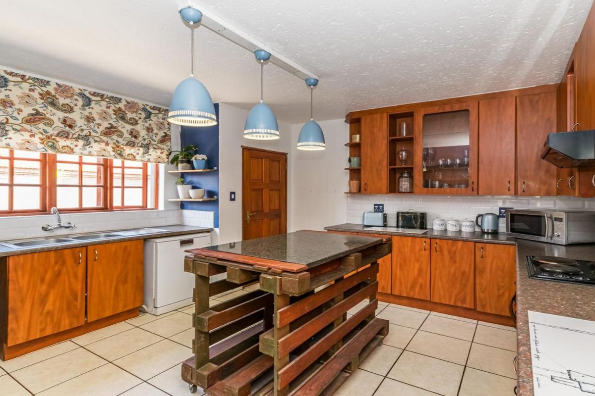 A functional kitchen featuring wooden cabinetry, laminate countertops, a double basin sink, and a built-in hob with an extractor fan.