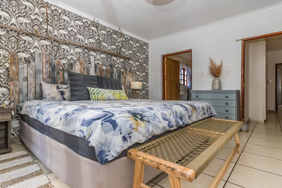 A bedroom featuring tiled flooring, coved ceilings, and a direct doorway leading to an ensuite bathroom.