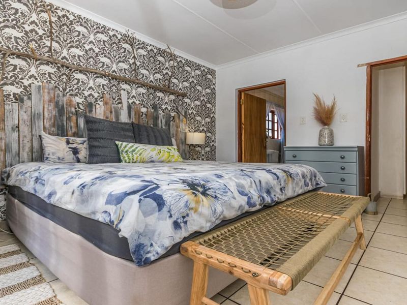 A bedroom featuring tiled flooring, coved ceilings, and a direct doorway leading to an ensuite bathroom.