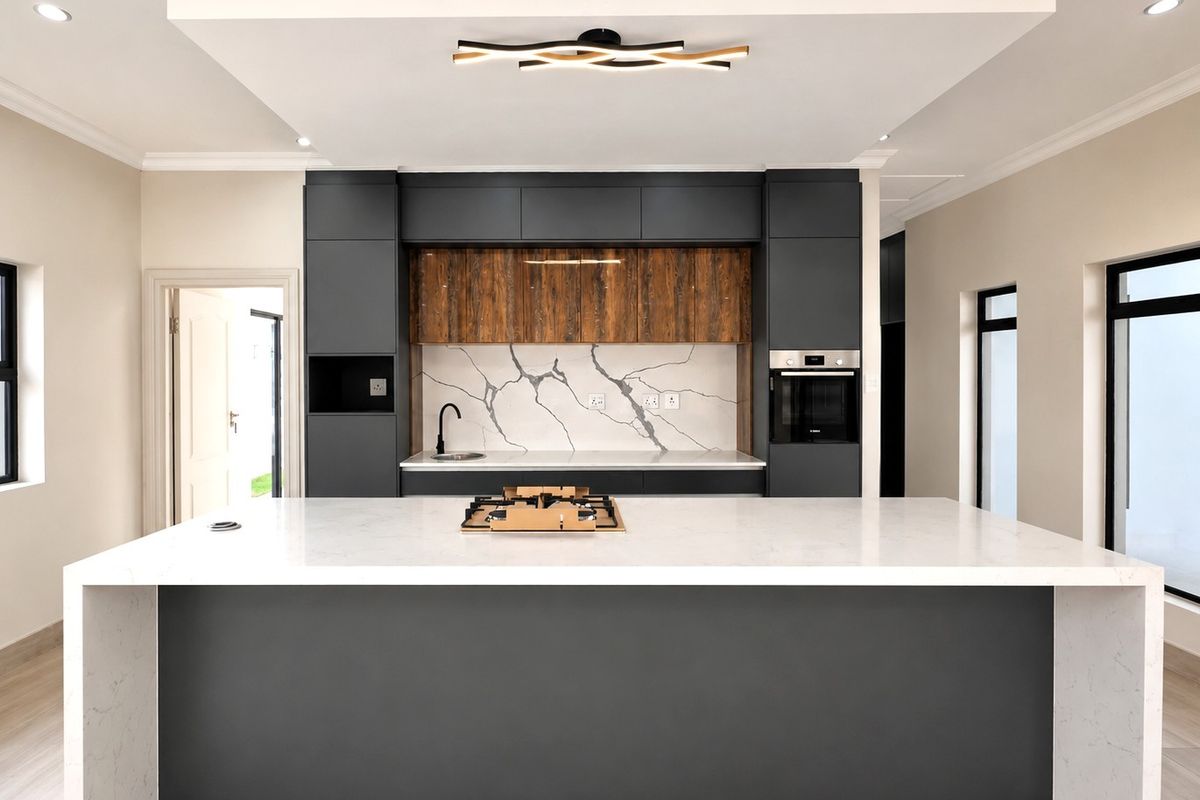 Modern kitchen featuring a large central island with quartz countertops, dark cabinetry, built-in oven, gas hob, and a stylish stone splashback.