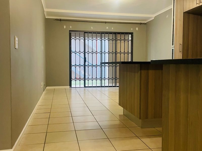 Open plan living area featuring ceramic tile flooring, a kitchen island with laminate cabinetry, and a sliding glass door with a security gate.