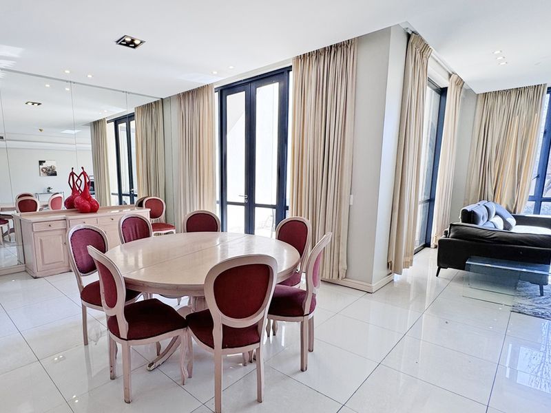 Spacious open-plan living and dining area featuring polished tile flooring, recessed lighting, and large glass doors providing ample natural light.