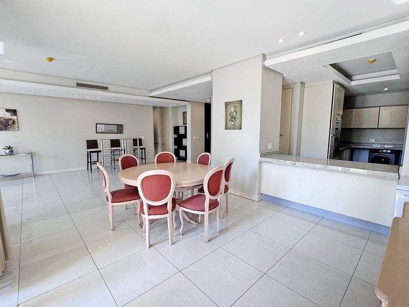 Spacious open-plan living and dining area featuring polished porcelain tiles, recessed lighting, and a functional kitchen with granite countertops and ample cabinetry.